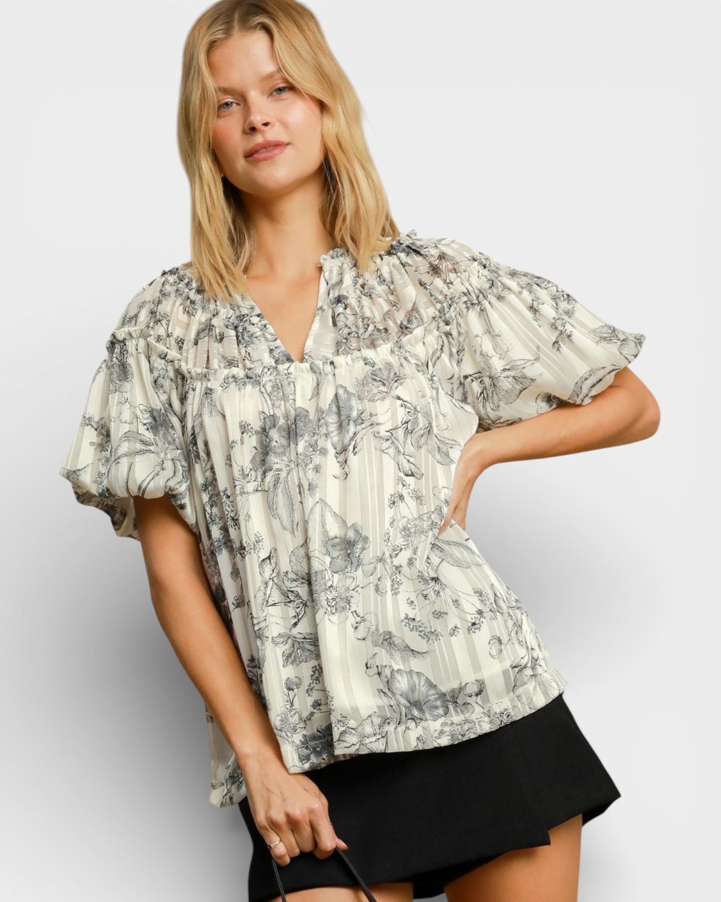 Woman wearing a floral blouse with ruffled sleeves on a plain background