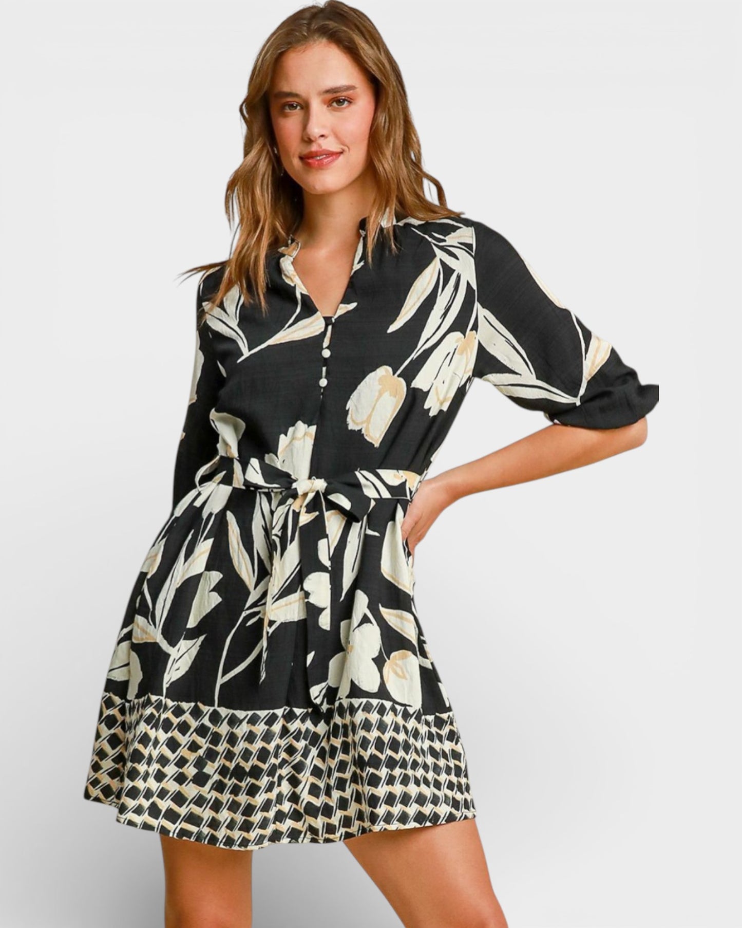 Woman wearing a black and white floral dress with a patterned hem on a white background