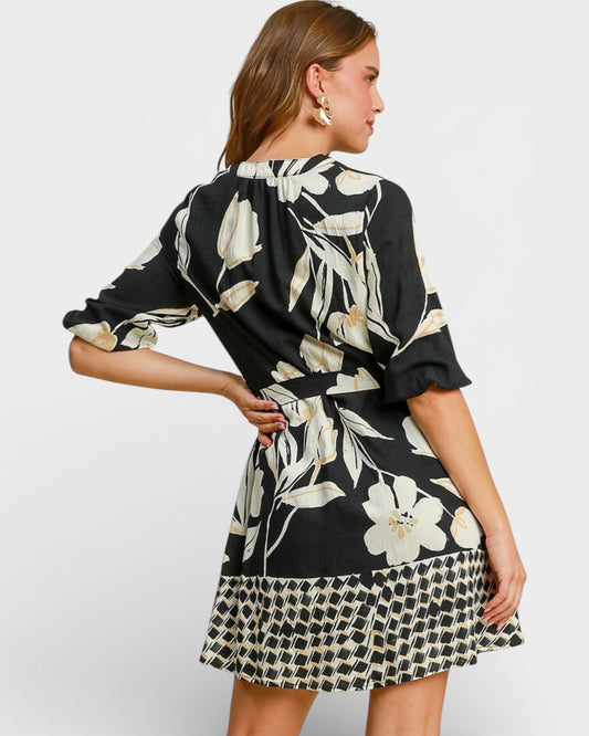 Woman wearing a black and white floral dress with a plain background