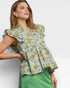 Woman wearing a floral blouse with ruffled sleeves on a white background