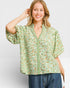 Woman wearing a green floral blouse against a white background