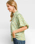 Woman wearing a green floral blouse against a white background