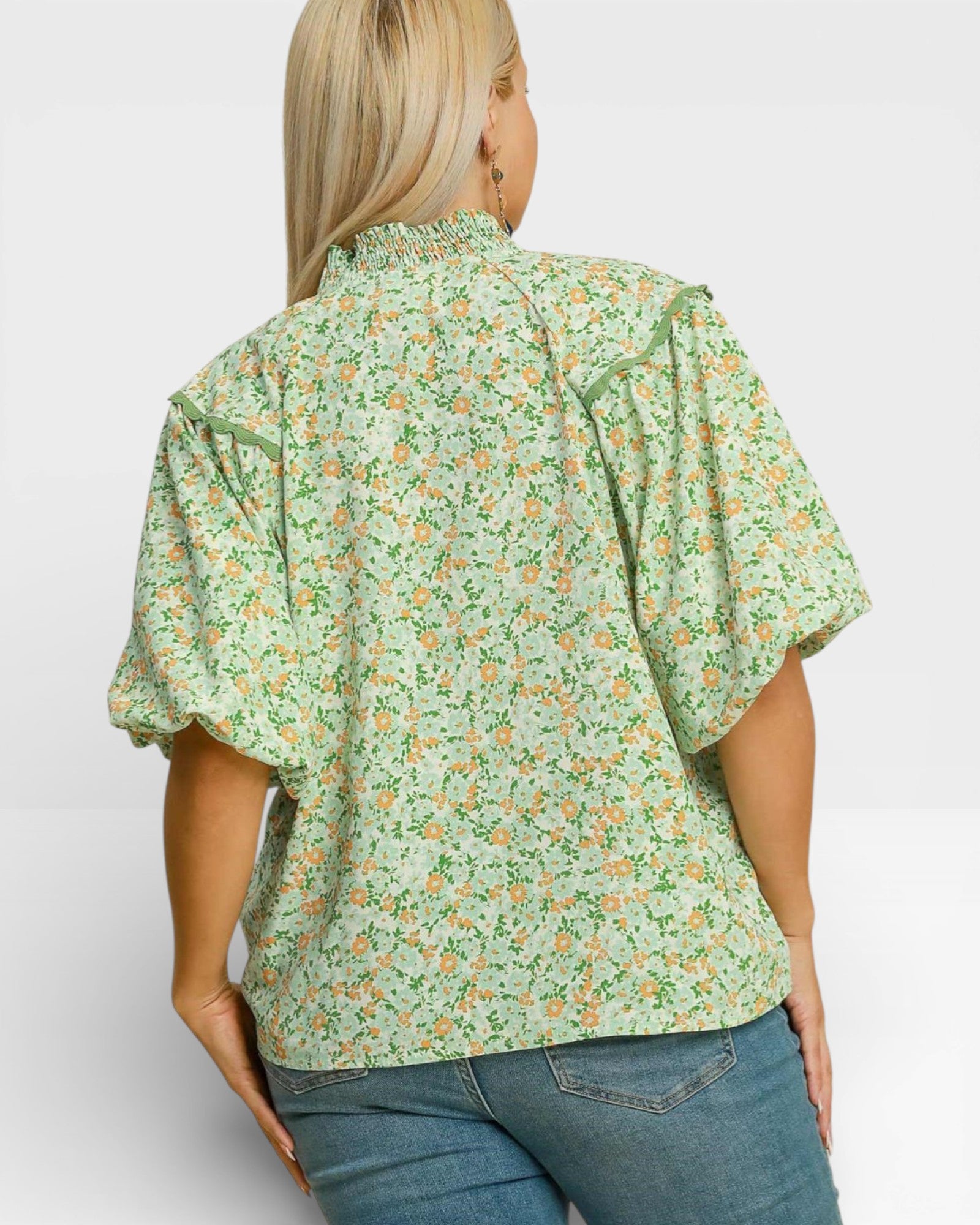 Woman wearing a green floral blouse with puffed sleeves on a white background