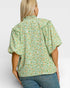 Woman wearing a green floral blouse with puffed sleeves on a white background