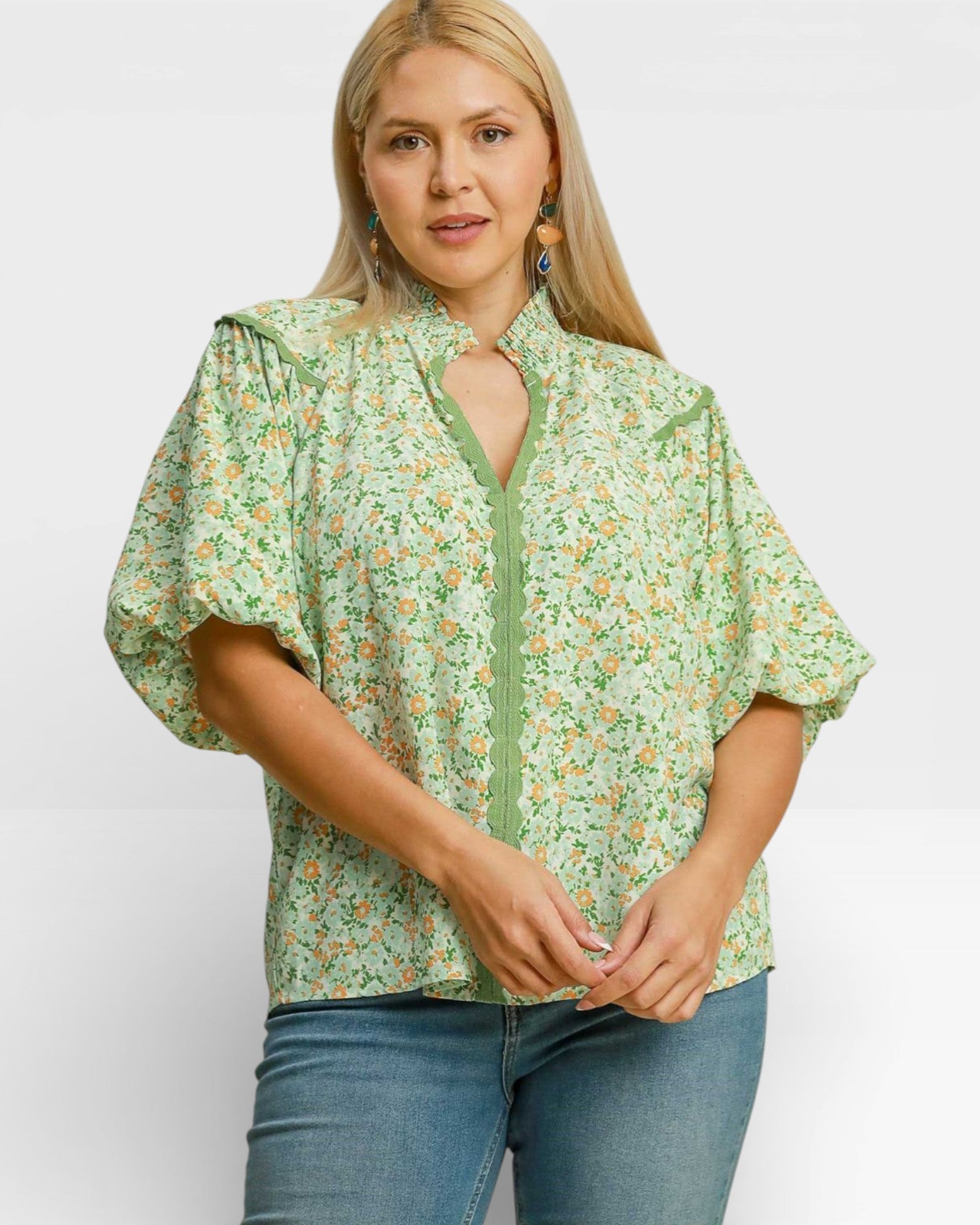 Woman wearing a green floral blouse with a plain background