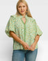 Woman wearing a green floral blouse with a plain background