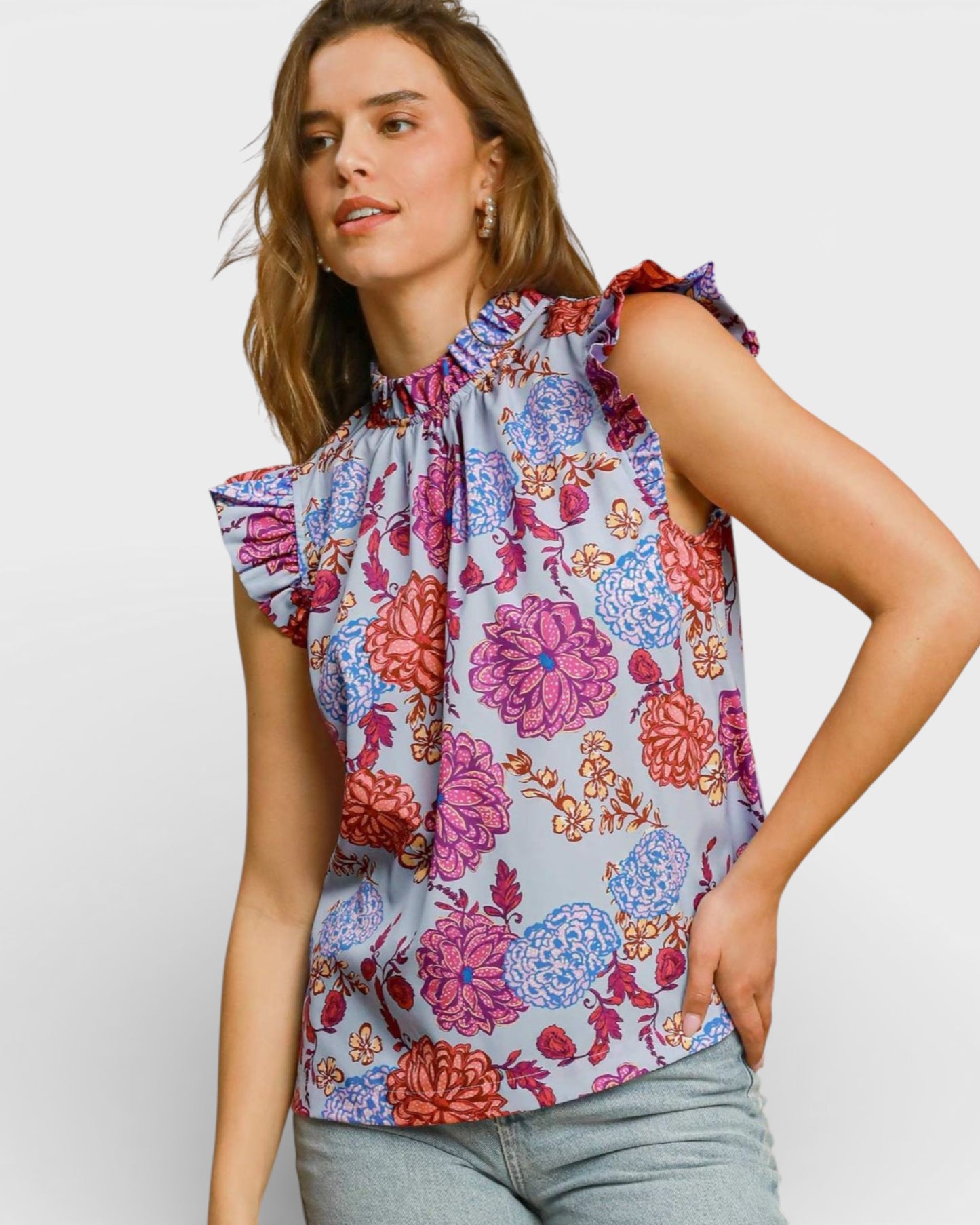 Woman wearing a colorful floral sleeveless top against a plain background