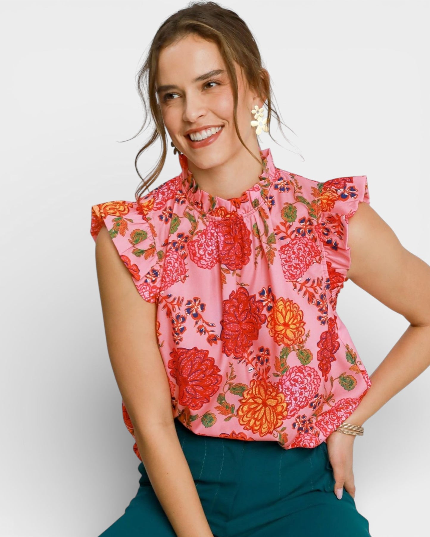 Woman wearing a pink floral blouse with green pants on a white background