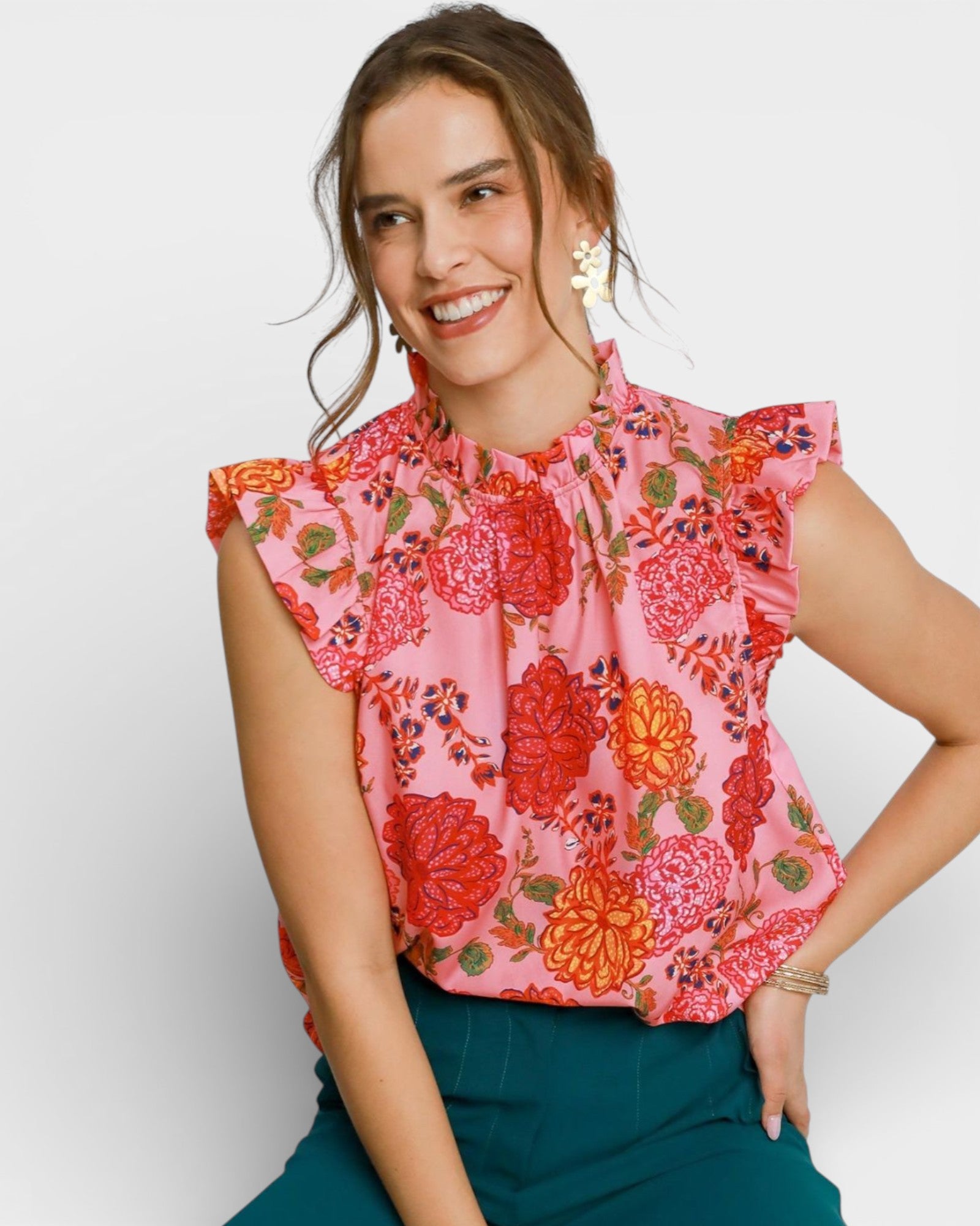 Woman wearing a pink floral blouse with green pants on a white background