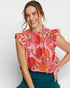 Woman wearing a pink floral blouse with green pants on a white background