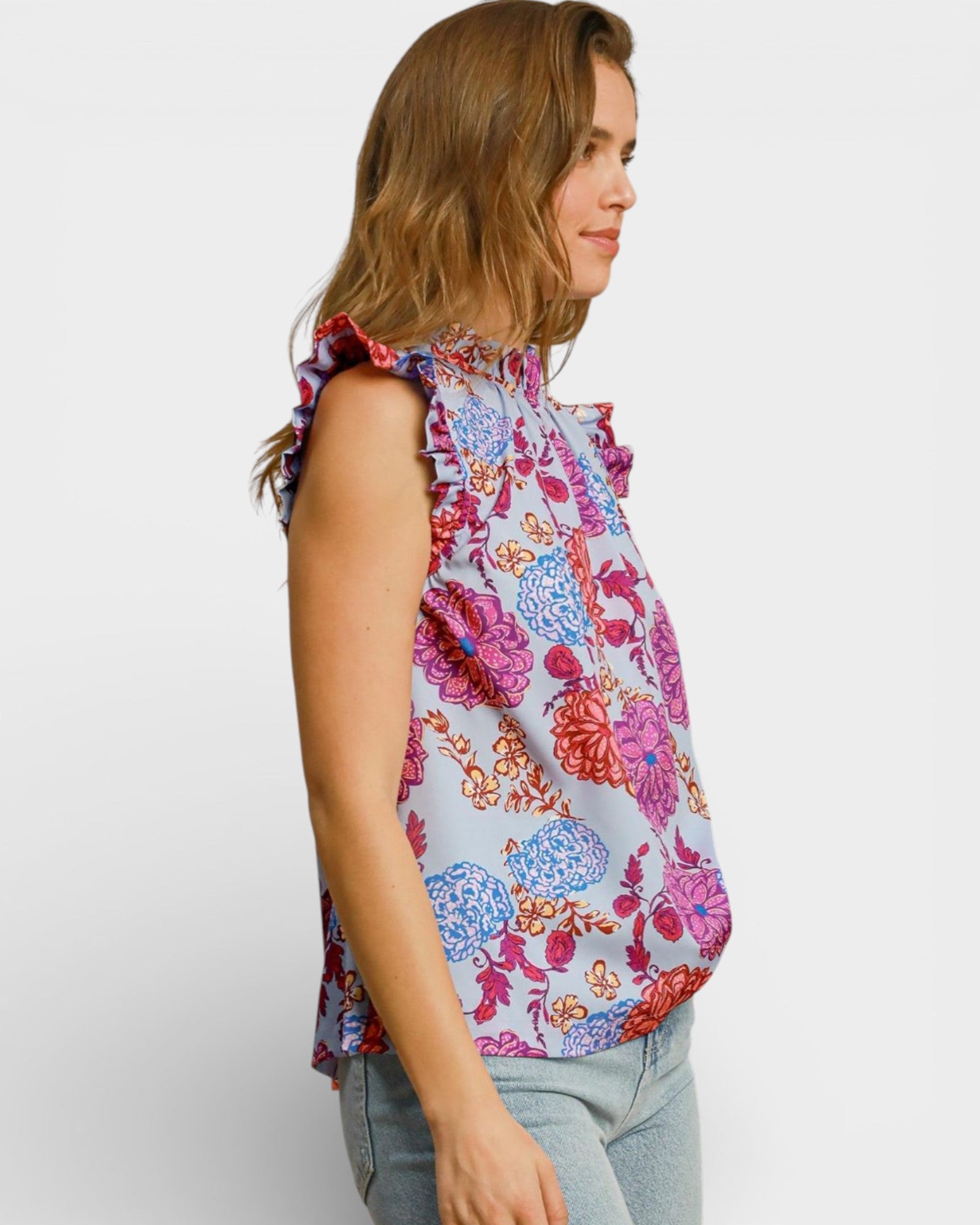 Woman wearing a colorful floral sleeveless top on a white background