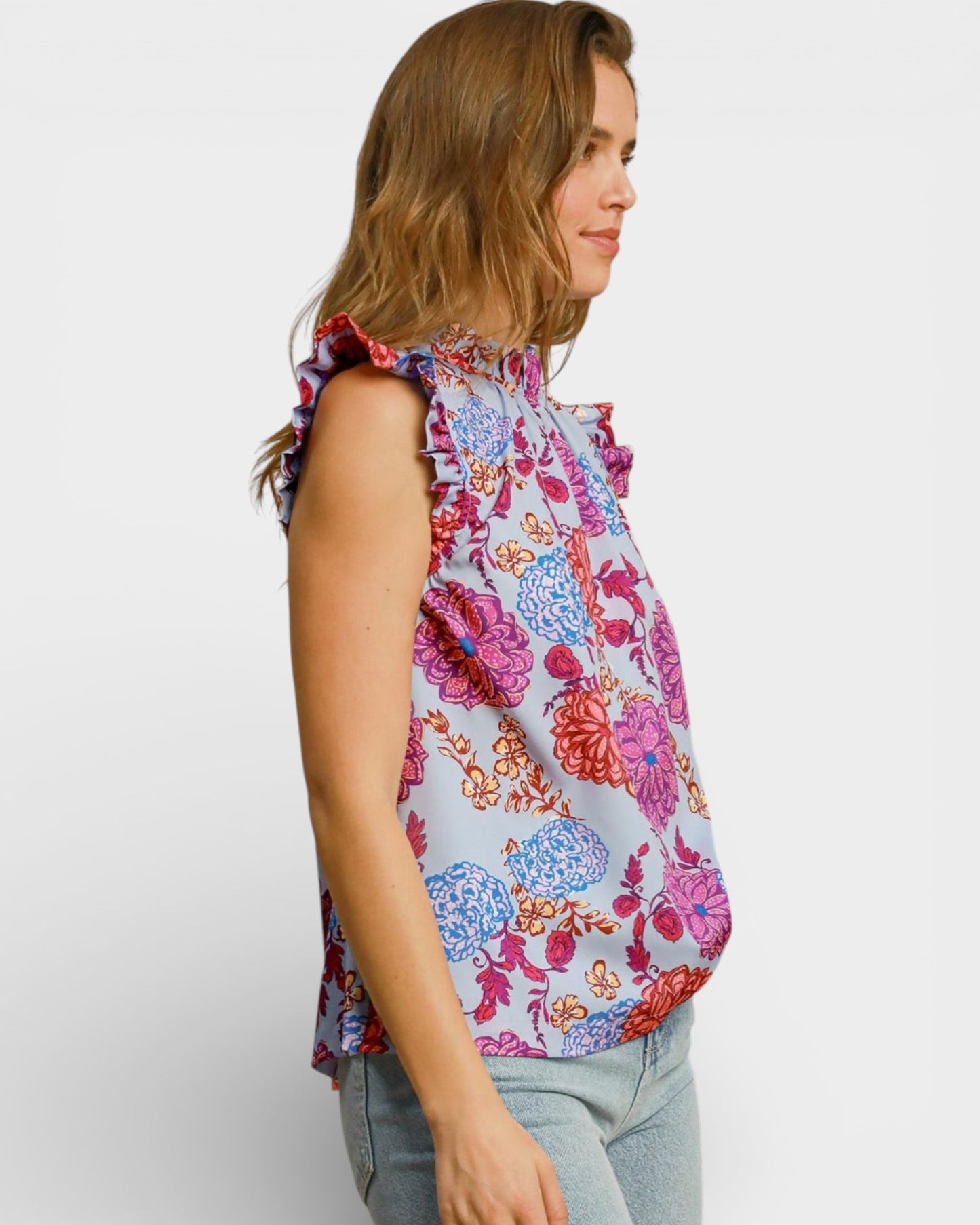 Woman wearing a colorful floral sleeveless top on a white background