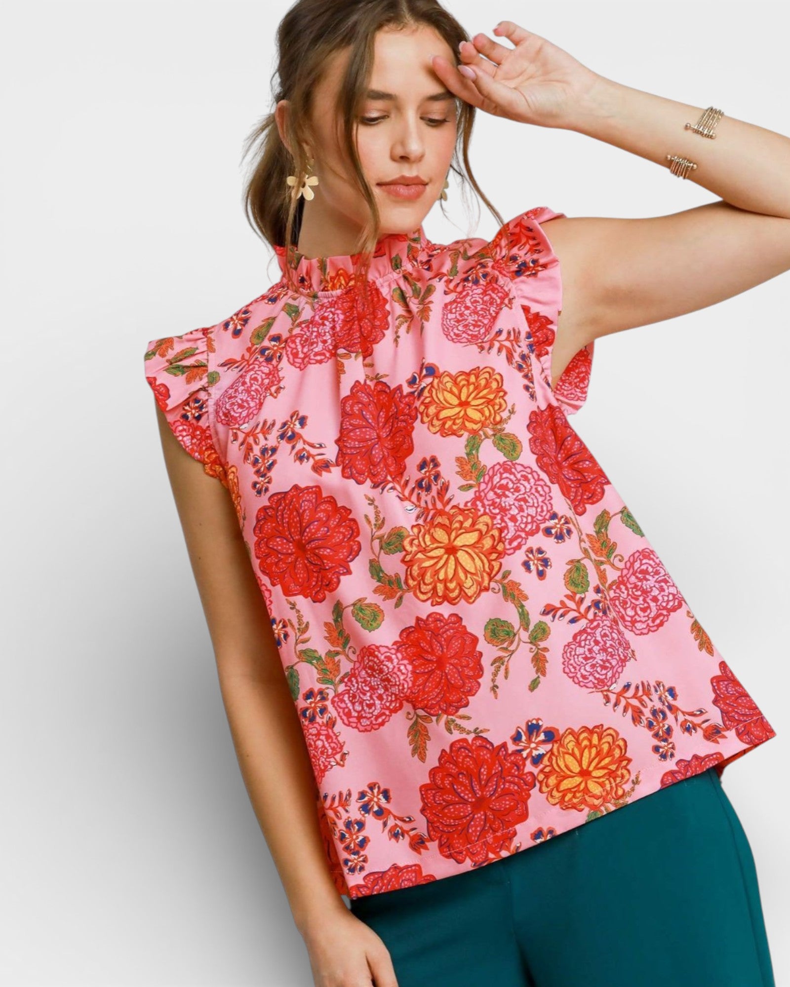 Woman wearing a sleeveless floral top with red and orange flowers on a pink background