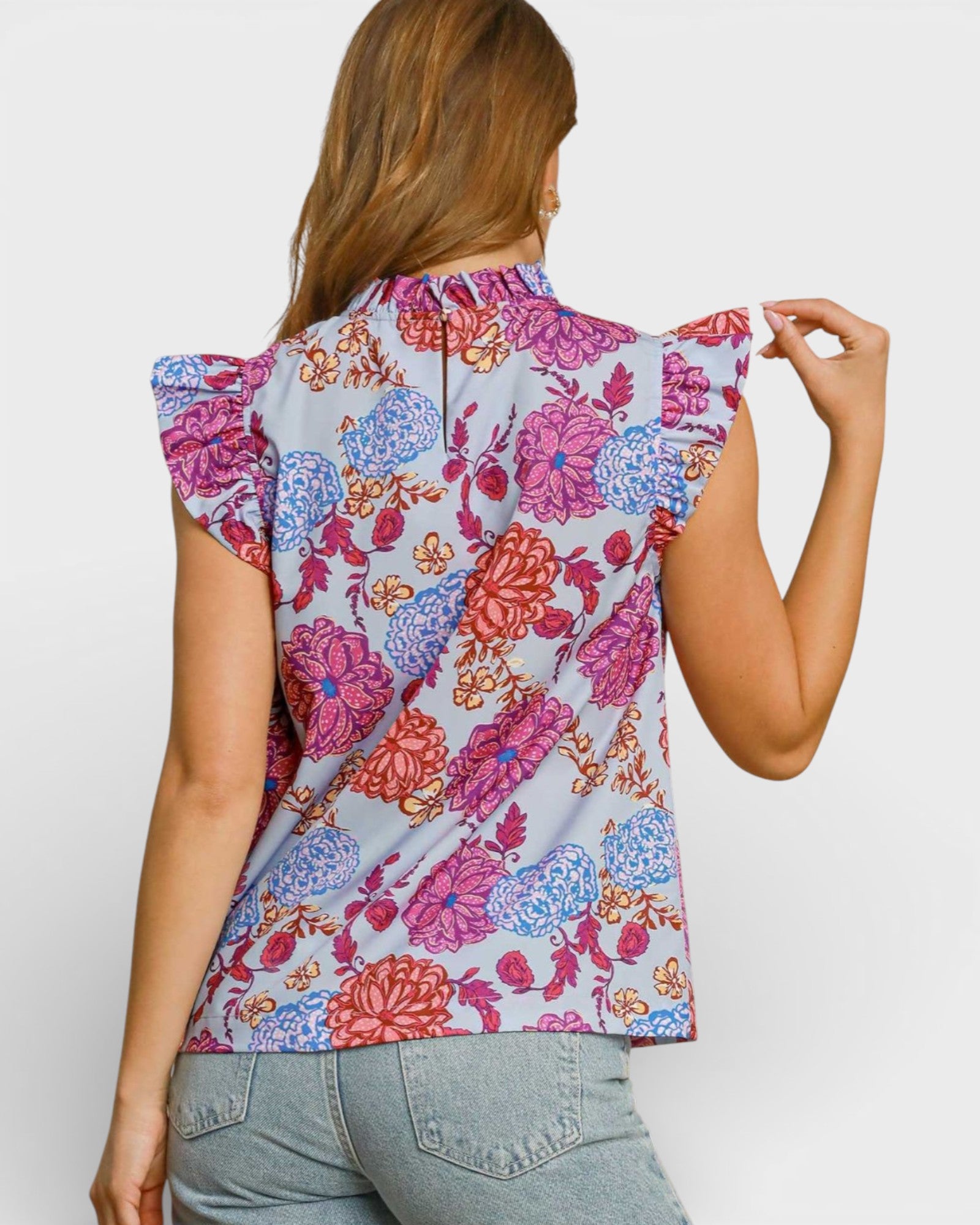 Woman wearing a sleeveless floral top with ruffled shoulders on a white background