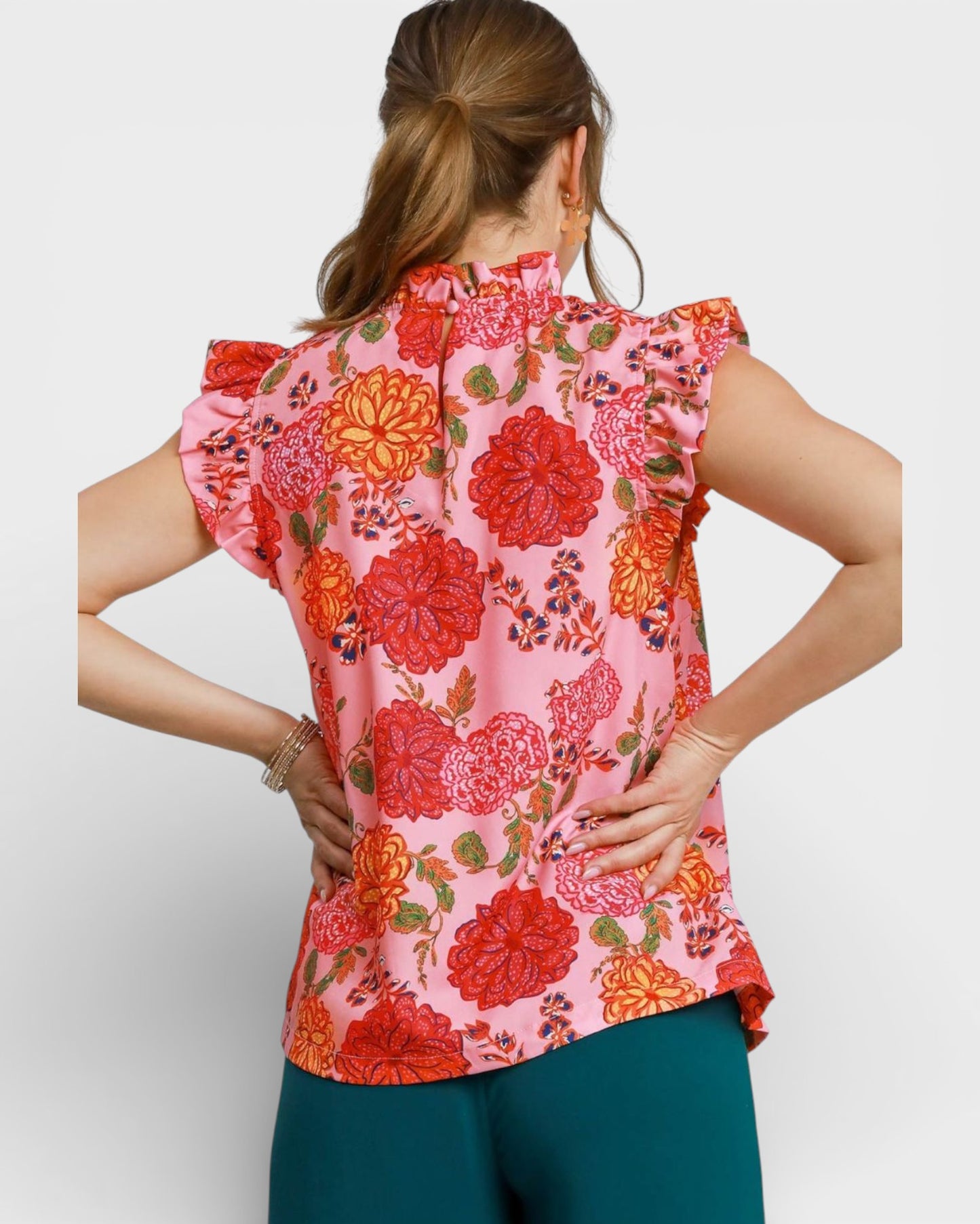 Woman wearing a sleeveless floral blouse with a white background
