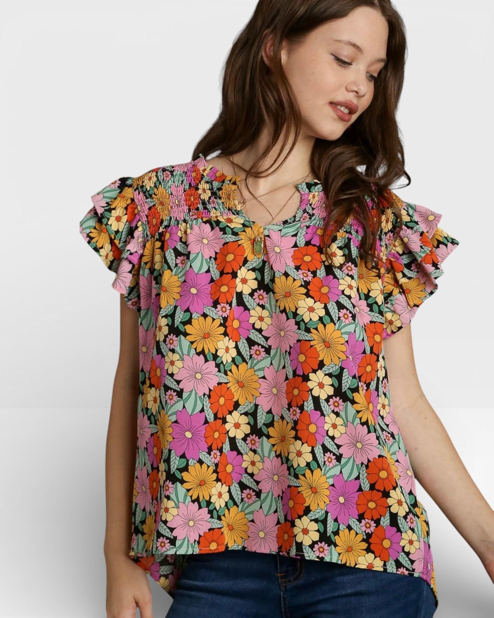 Woman wearing a colorful floral blouse against a plain background