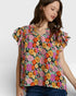 Woman wearing a colorful floral blouse against a plain background