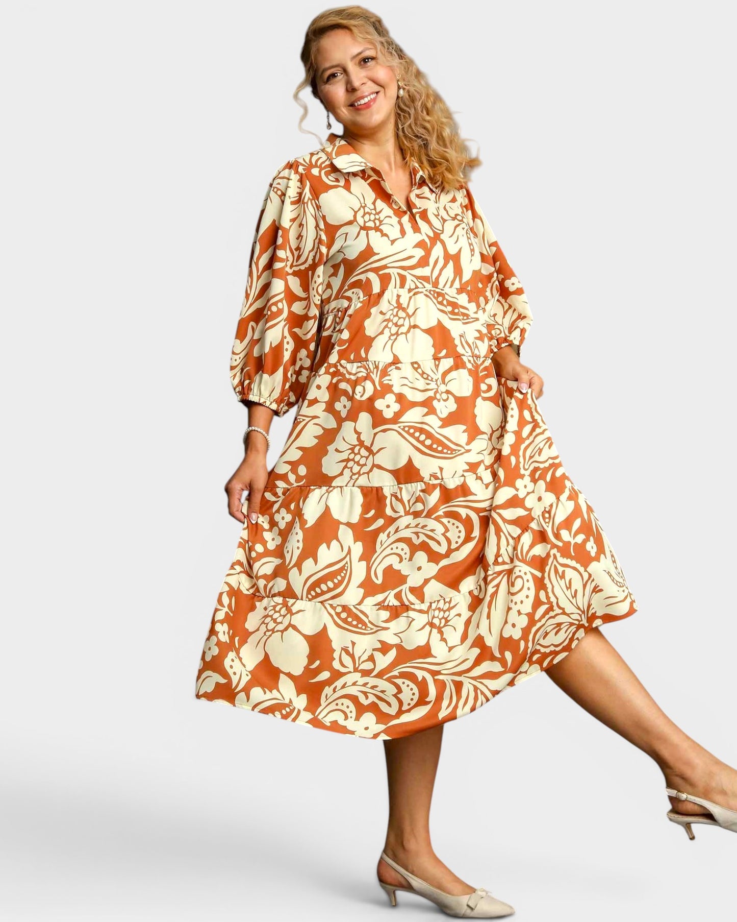 Woman wearing an orange and white floral dress on a plain background