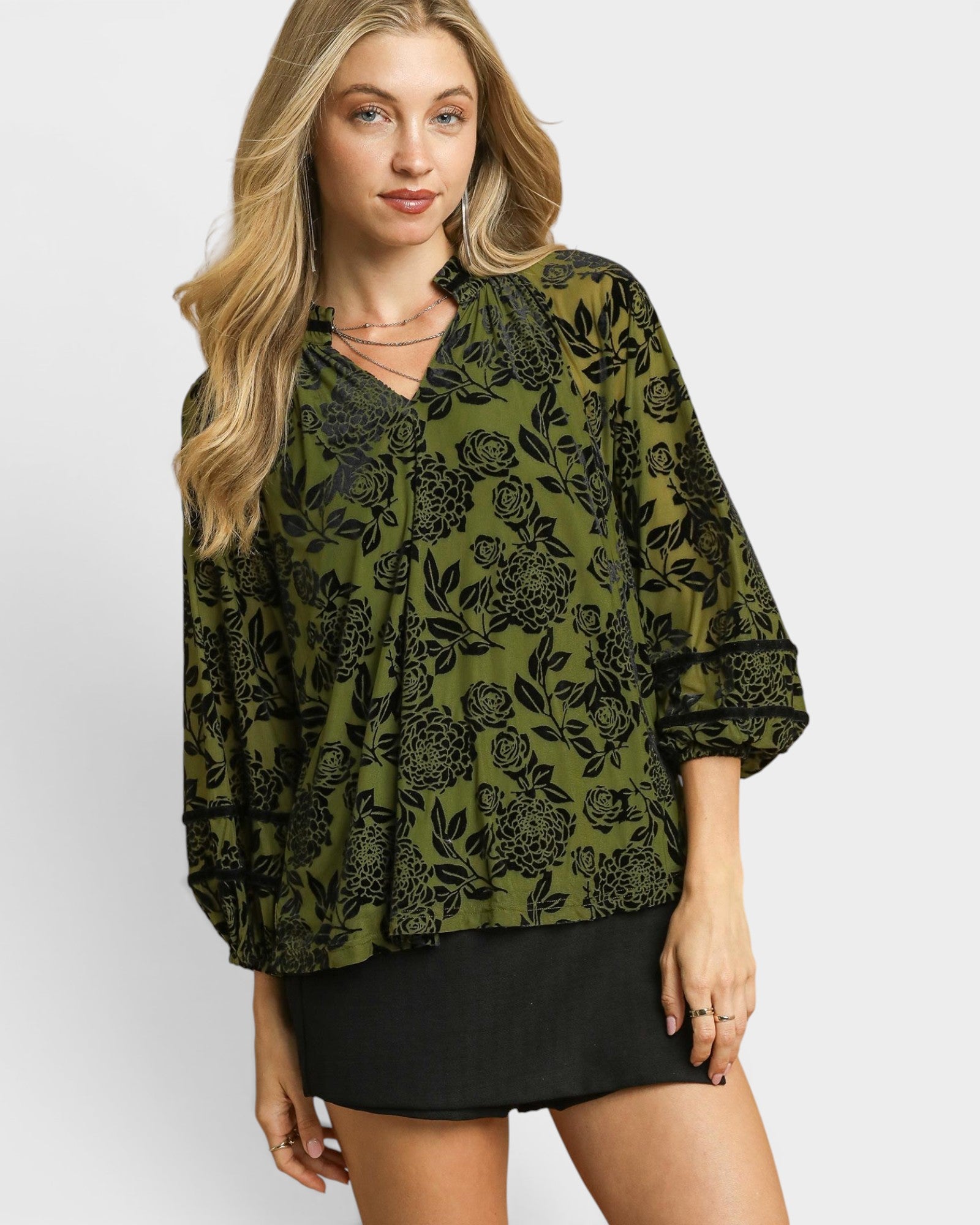 Woman wearing a green floral blouse with a plain background