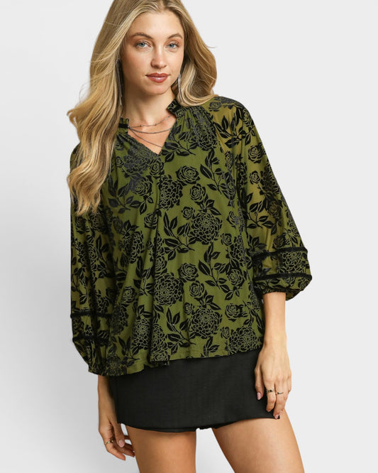 Woman wearing a green floral blouse with a plain background