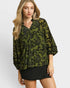 Woman wearing a green floral blouse with a plain background