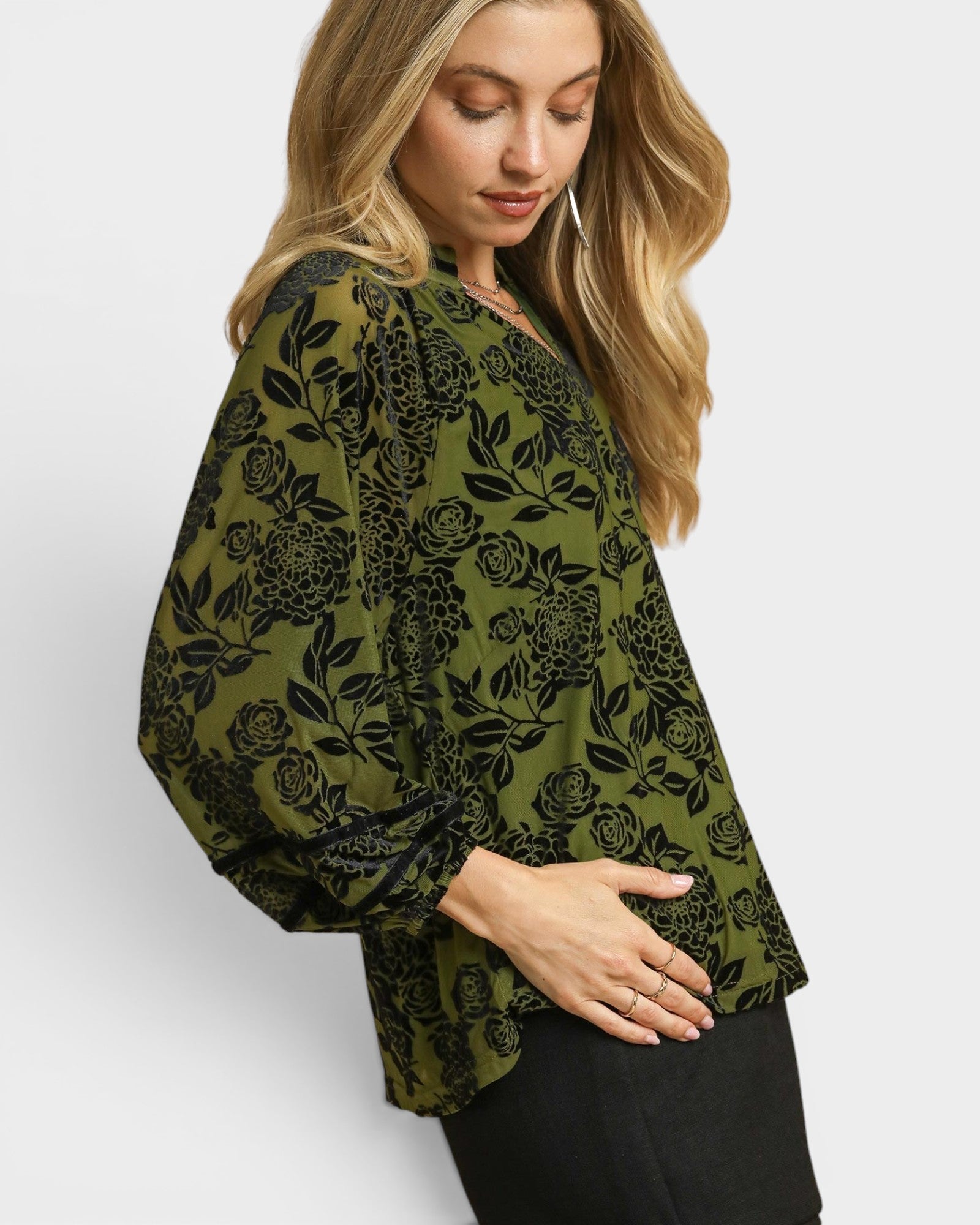 Woman wearing a green floral patterned top on a white background