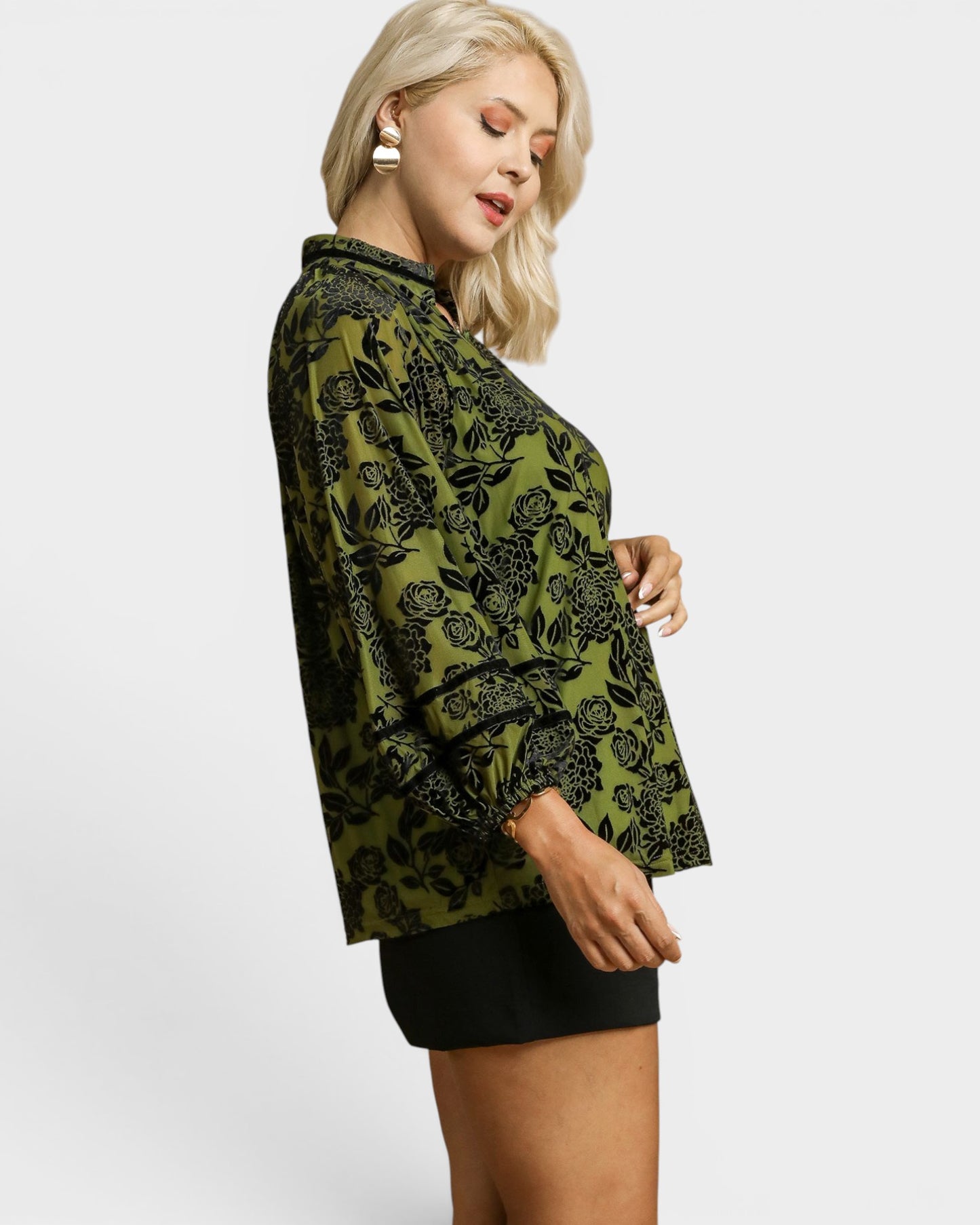 Woman wearing a green patterned blouse on a white background
