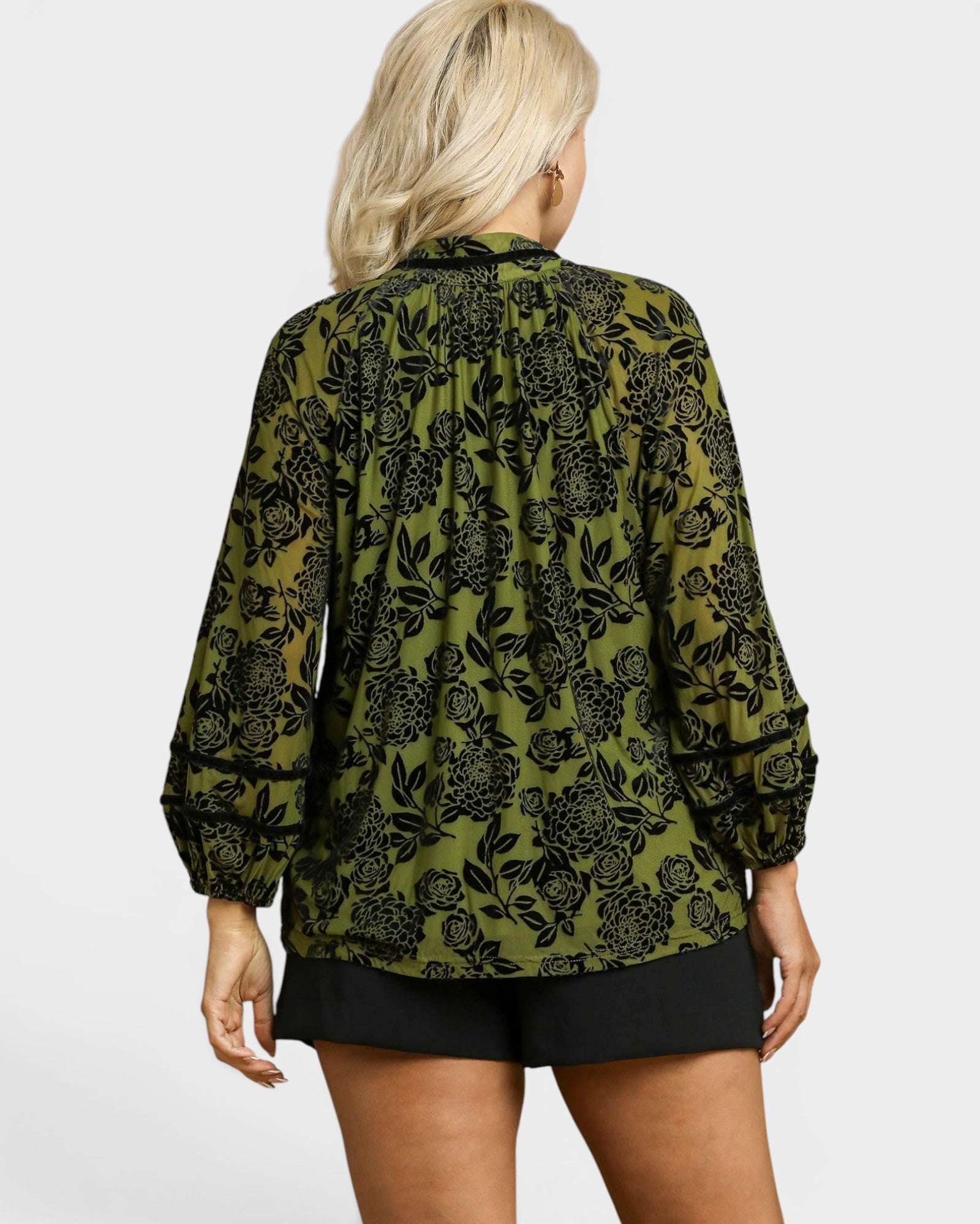 Person wearing a green floral patterned blouse on a white background