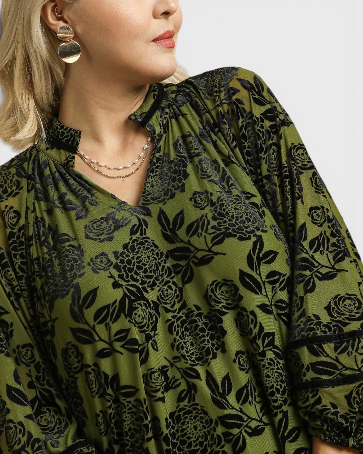 Woman wearing a green floral patterned dress with a plain background