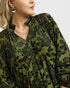Woman wearing a green floral patterned dress with a plain background