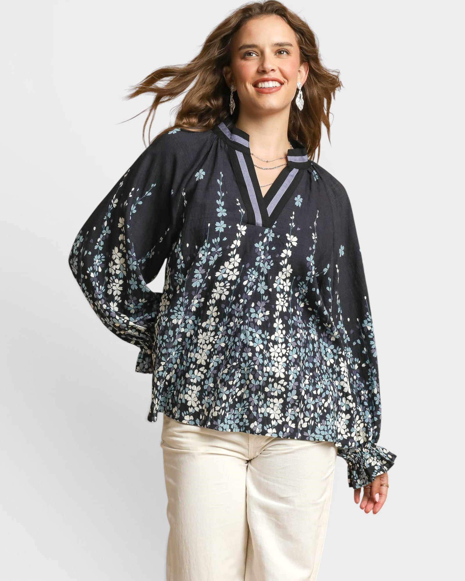Woman wearing a black floral blouse with long sleeves on a white background