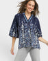 Woman wearing a navy floral blouse with gray pants on a light gray background