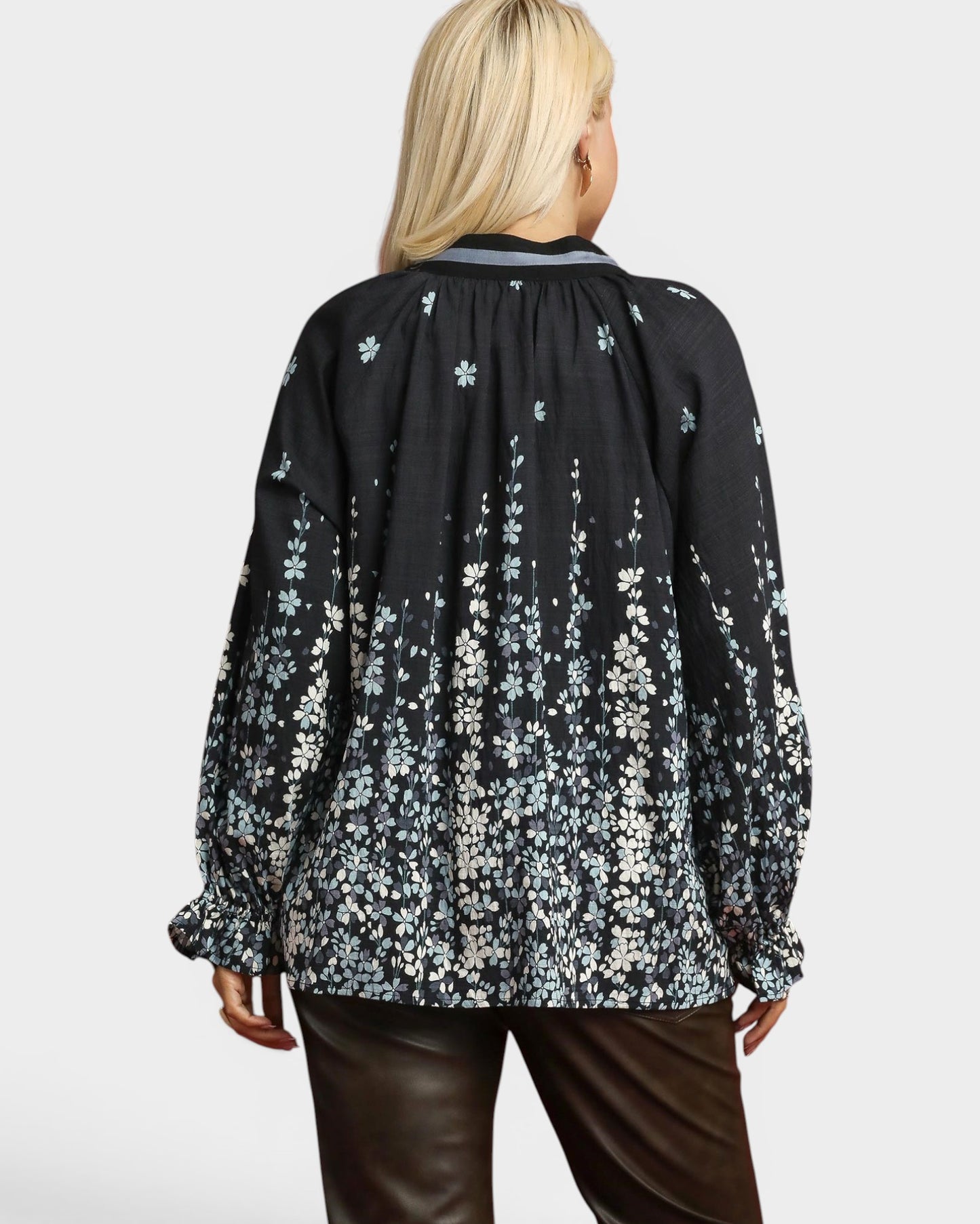 Person wearing a black floral blouse with a plain background
