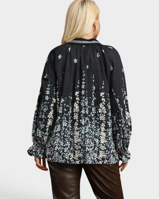 Person wearing a black floral blouse with a plain background
