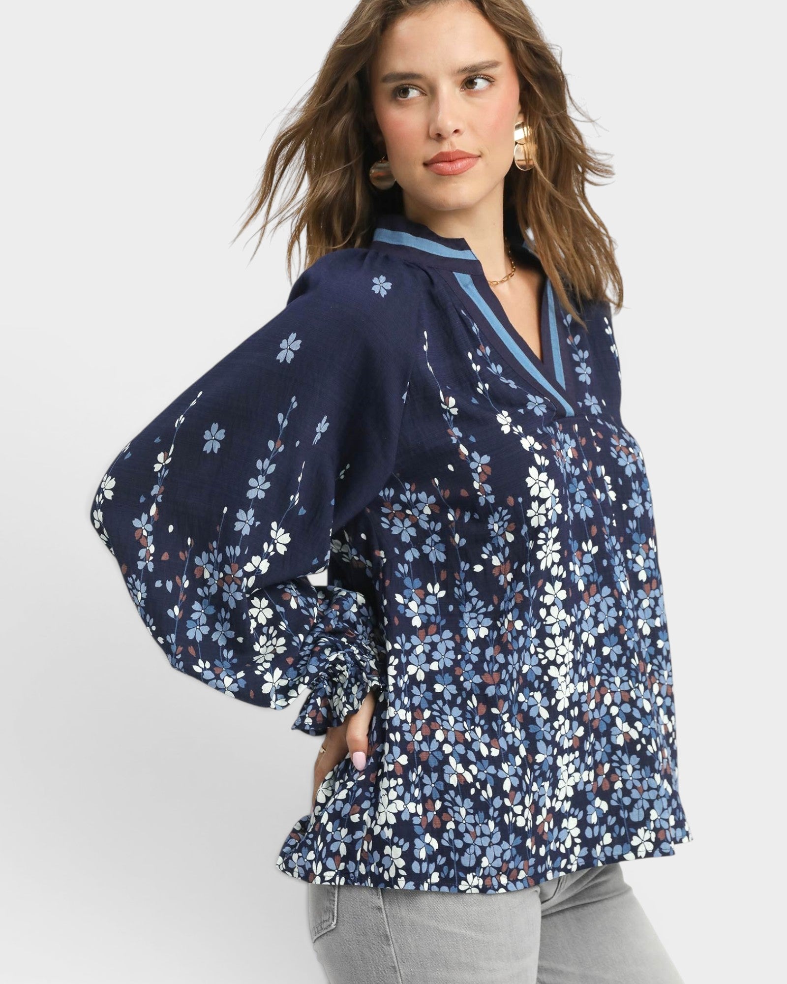 Woman wearing a navy floral blouse on a light gray background