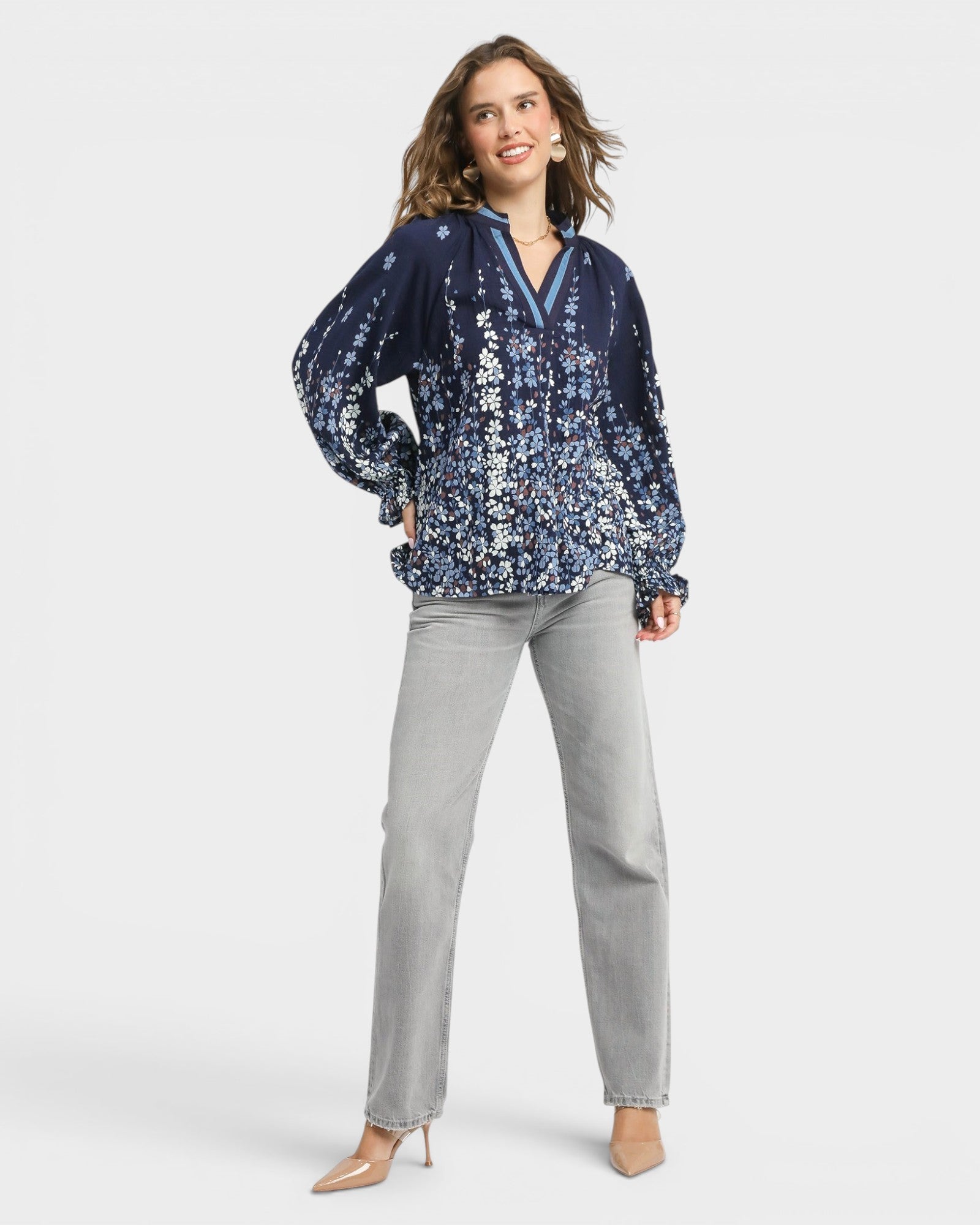 Woman wearing a blue floral blouse and gray pants on a white background