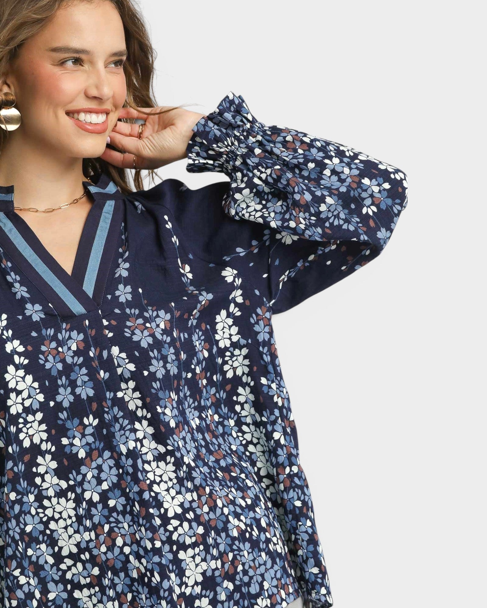 Woman wearing a navy floral blouse with a plain background