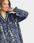 Woman wearing a navy floral blouse with a plain background
