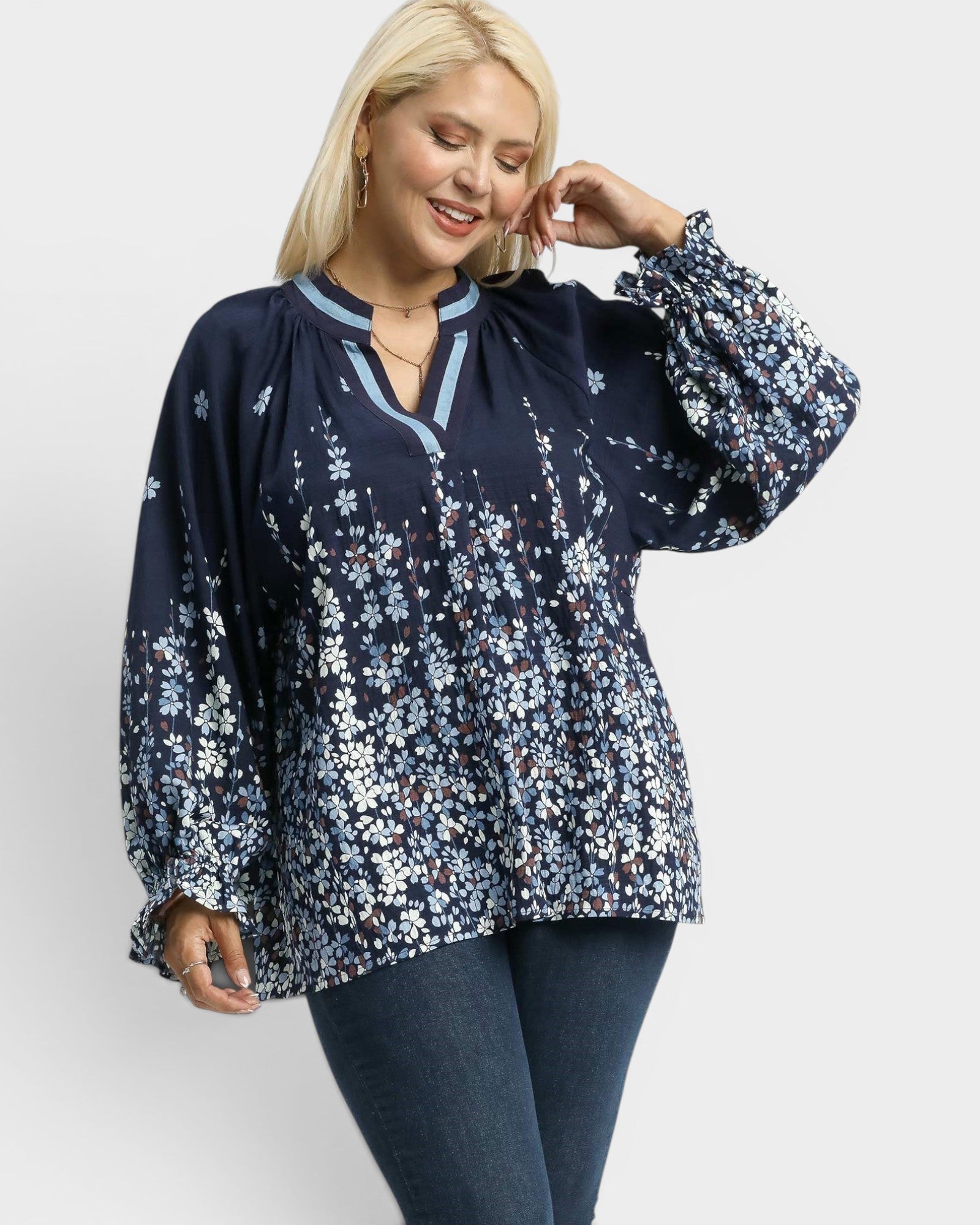 Woman wearing a navy floral blouse with long sleeves on a white background
