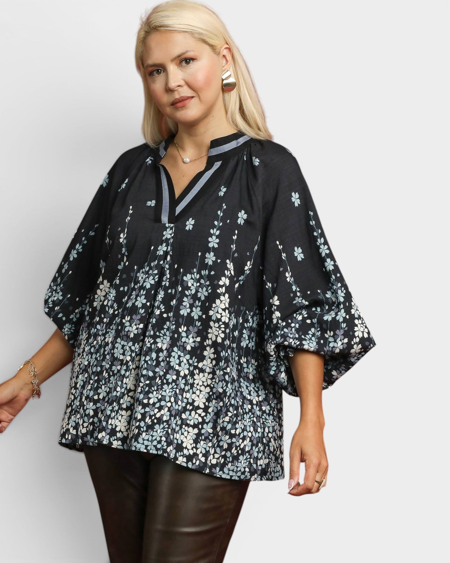 Woman wearing a black floral blouse against a white background