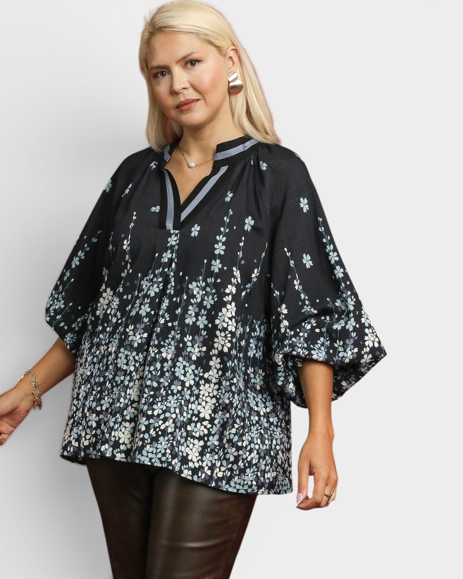Woman wearing a black floral blouse against a white background