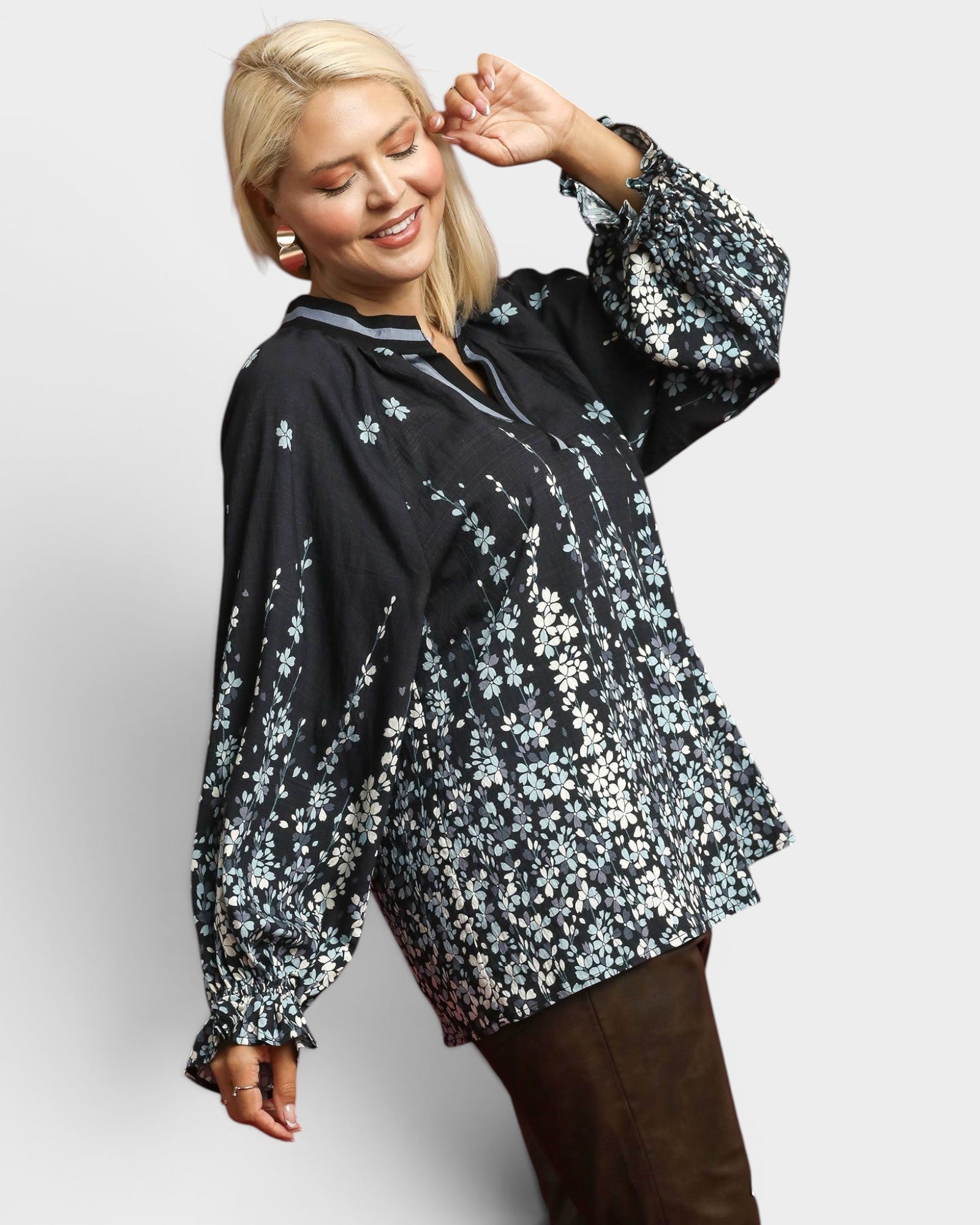 Woman wearing a black floral blouse against a light gray background
