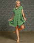 Woman wearing a green dress against a brick wall.
