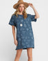 Woman wearing a blue patterned dress and brown hat on a white background