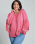 Woman wearing a pink sweater with fringe details on a gray background