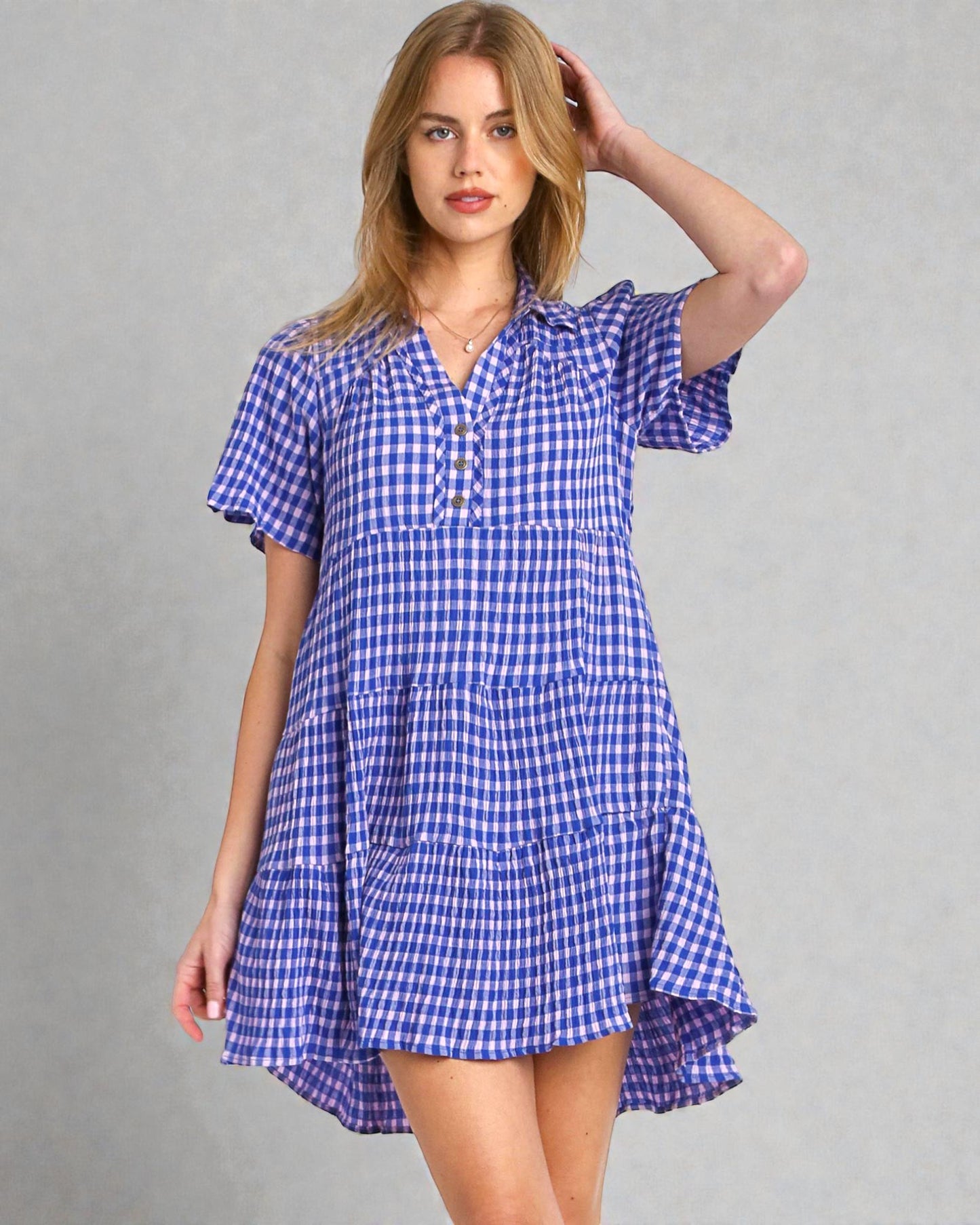Woman wearing a blue and white checkered dress against a gray background