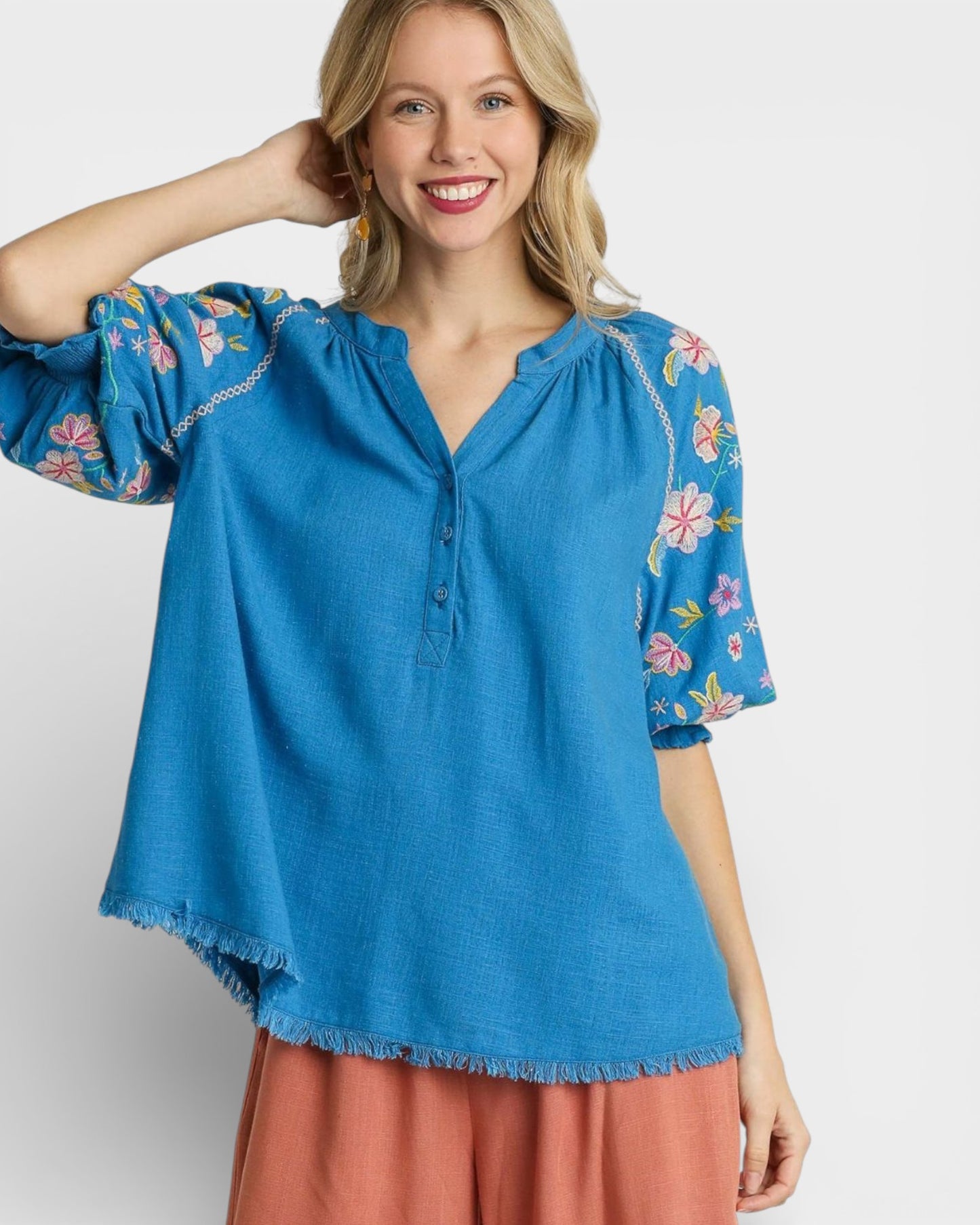 Woman wearing a blue floral blouse with a plain background