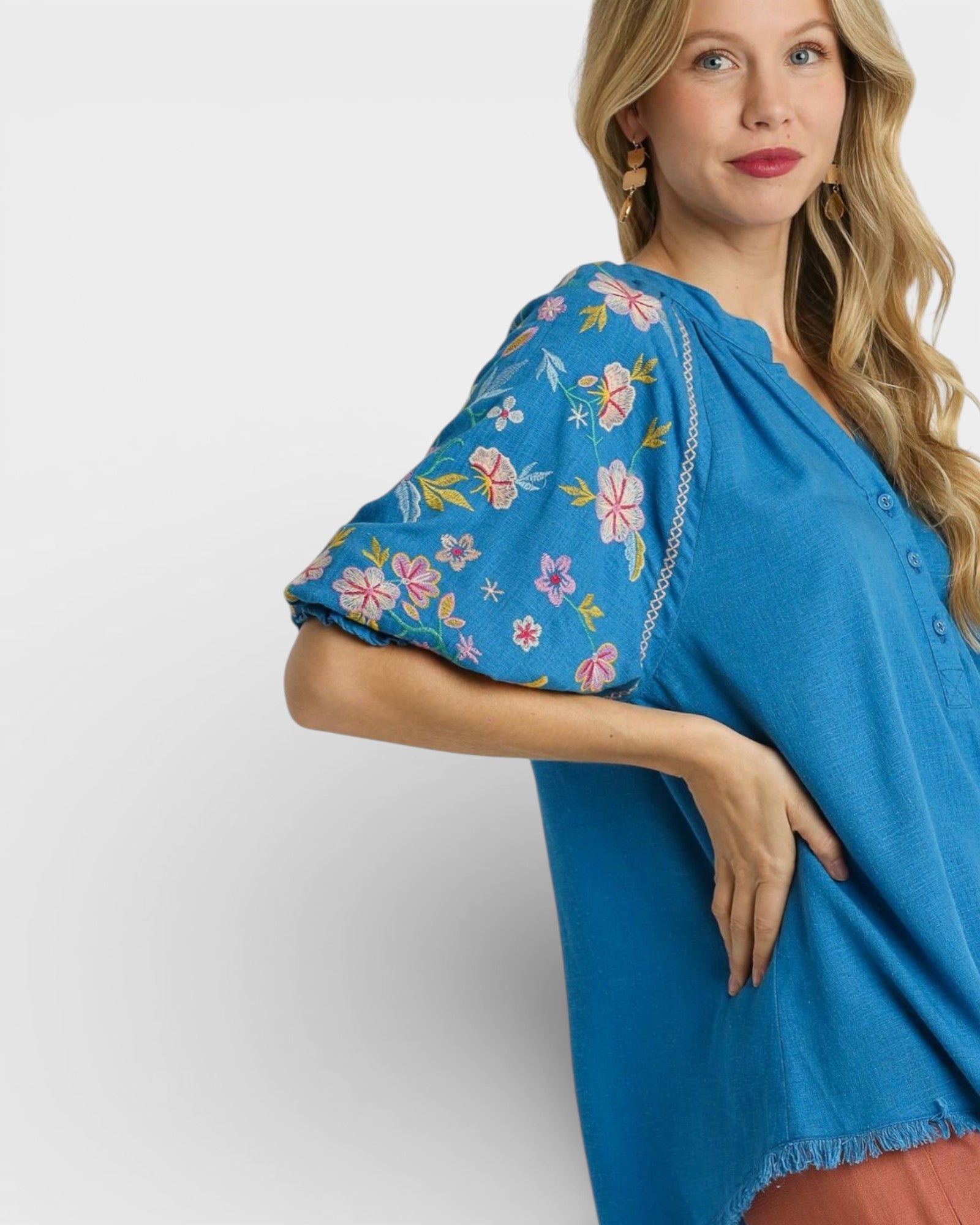 Woman wearing a blue dress with floral embroidery on a white background
