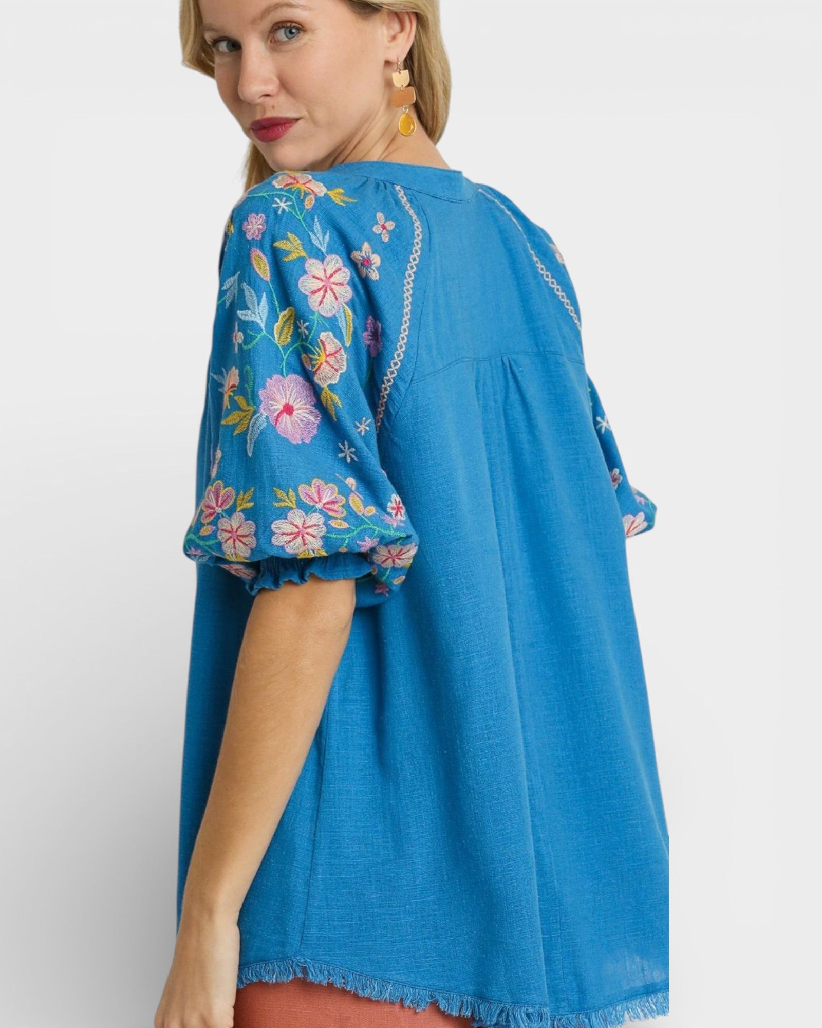 Woman wearing a blue dress with floral embroidery on a white background
