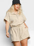 Woman wearing a beige romper and black hat on a white background